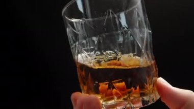 Bardakta viski çeviriyorum, yakın plan. Siyah bir arka planda. Kapat.