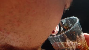 Sakallı bir adam bardakta viski koklar, çok yakından..