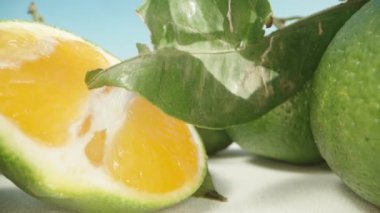 Mavi gökyüzüne karşı ikiye bölünmüş yeşil mandalinalar. Dolly kaydırıcı aşırı yakın çekim.