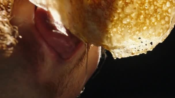パンケーキから蜂蜜が滴り落ち男が噛んだ 黒い背景の上に — ストック動画