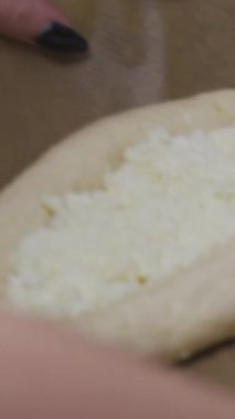 Genç bayan geleneksel Khachapuri 'yi yumurtalı hazırlıyor. Hamur ve peynir, fırına dikey video koyun..