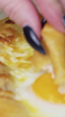 Genç kadın bir parça khachapuri 'yi yumurtaya daldırıyor, yavaş çekim, dikey video.