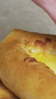 Genç kadın bir parça khachapuri 'yi yumurtaya daldırıyor, yavaş çekim, dikey video.