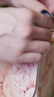 Pasta şefi genç bir kadın hediye kutusuna çöreklerle fiyonk bağlıyor. Dikey video.