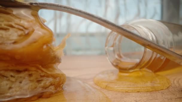 トルコのお菓子と蜂蜜の瓶がテーブルの上にあり 蜂蜜がそれらを通って流れています カメラはテーブルを横切った 指で蜂蜜を飲む — ストック動画