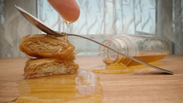 トルコのお菓子と蜂蜜の瓶がテーブルの上にあります 指が蜂蜜の中にあり スプーンに触れる — ストック動画