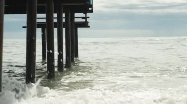 Sütunlar, metal iskele destekli denizler, aşağıdan manzara, dalgalar onlara çarpıyor..