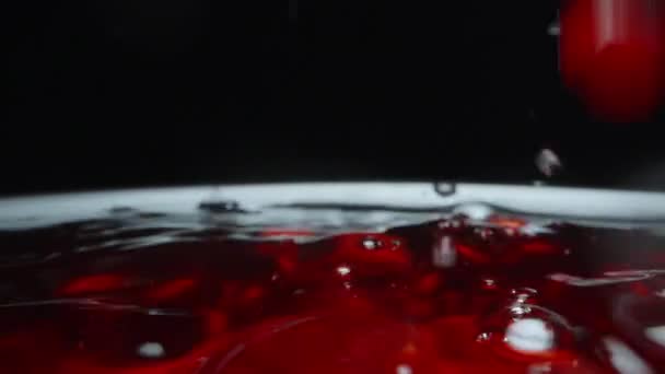 ザクロの種子は黒の背景に赤いジュースに落ちる スローモーション ドリー スライダー 極端なクローズアップ — ストック動画
