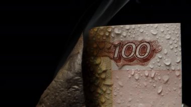 Banknottan duman, siyah arka planda su damlaları olan Rus yüz rublesi. Yakın plan..