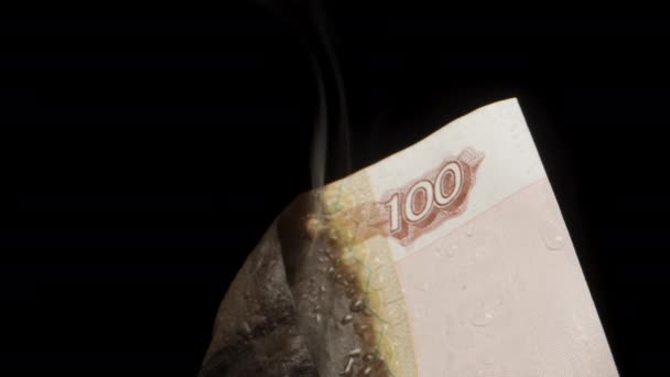 从钞票上冒出的烟 俄罗斯100卢布 水滴在黑色的背景上 后续行动 — 图库视频影像