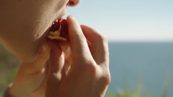 Die Junge Frau Beißt Einen Granatapfel Auf Dem Hintergrund Des — Stockvideo