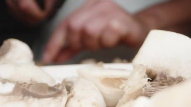 Kamera bir tabak doğranmış mantarın üzerinden geçer, bıçaklı bir kızın arka planına karşı. Kaydırıcı, makro çekim