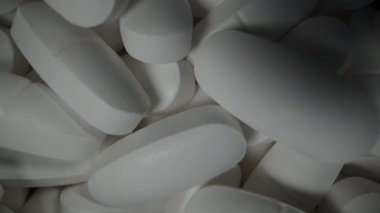 Siyah arka planda dönen beyaz tabletli siyah bir kavanoz. Dolly Slider aşırı yakın çekim. Üst görünüm.