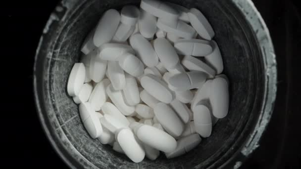 Ein Schwarzes Gefäß Mit Weißen Tabletten Rotiert Auf Schwarzem Hintergrund — Stockvideo
