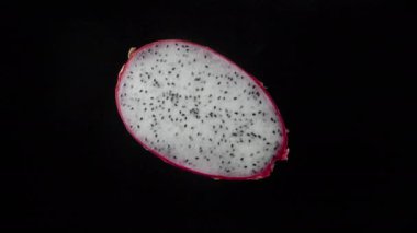 Beyaz tenli pitahaya 'nın yarısı siyah arka planda döner..