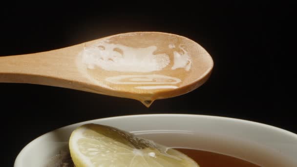 Honig Tropft Aus Einem Holzlöffel Auf Die Zitrone Tee Nahaufnahme — Stockvideo