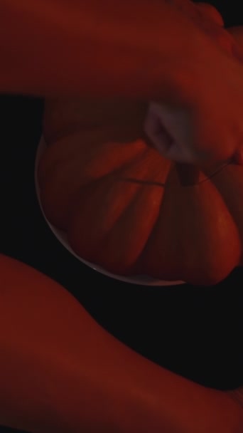 Függőleges Videó Egy Fiatal Tököt Vág Halloweenkor Vörös Fényben Felülnézet — Stock videók