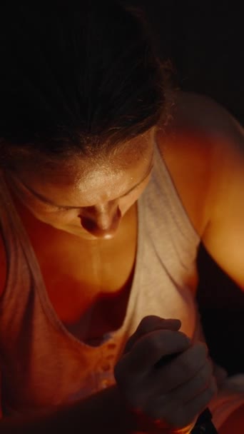 バーティカルビデオ 夜になると 若い女性がハロウィーンのカボチャを彫り カボチャの中の火が彼女を照らします 彼女の顔は汗で輝いている クローズアップショット — ストック動画
