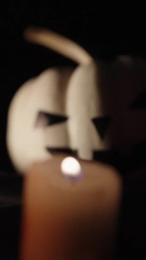 Dikey video. Cadılar Bayramı balkabakları, odak noktası beyaz balkabağından muma kayar. Yakın plan..