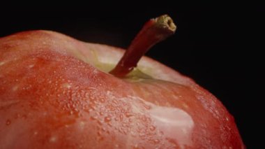 Kırmızı bir elmanın sapına bir damla su düşer. Ağır çekim, makro.
