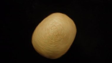 Kivi hızlı döner ve ikiye bölünür. Siyah arkaplan, yakın plan.