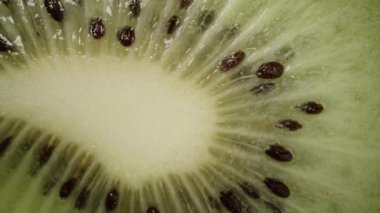 Kivi kes, küçük kemikli. Ekstrem makro, zoom. Yavaşça düşüyor ve uzaklaşıyor. İzole edilmiş siyah arka plan. Döndürme.