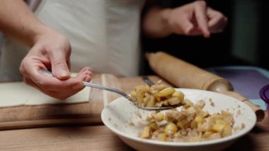 Genç kadın hamurun üzerine elma ve fındık doldurdu.