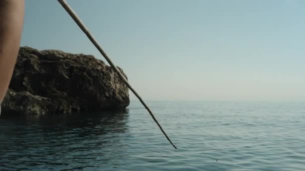 水着の若い女性が海で釣りをしている 自家製の竹釣り棒 女の子の浮遊物からの眺め — ストック動画