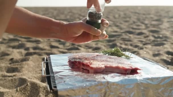 海のバーベキュー 砂の上にポータブルバーベキューがあり 私はフライする前にステーキを唐辛子 — ストック動画