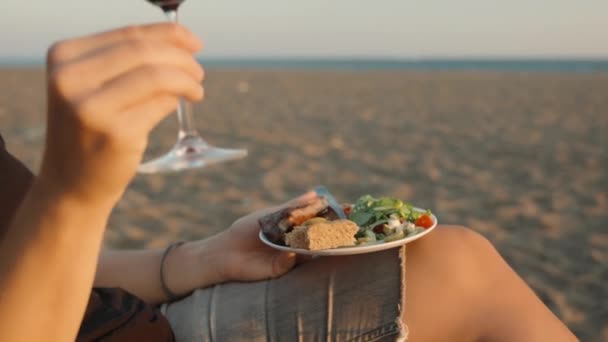 海滨的浪漫约会 一个拿着一盘肉 沙拉和红酒的年轻女子 愉快地闭上眼睛 — 图库视频影像