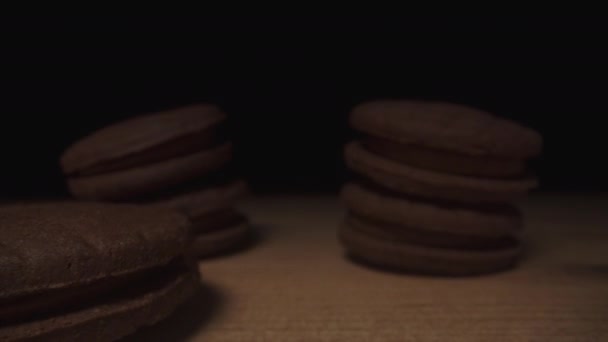 마카롱과 비슷한 초콜릿 쿠키가 테이블의 그림자에서 나타나고 카메라가 미끄러집니다 — 비디오