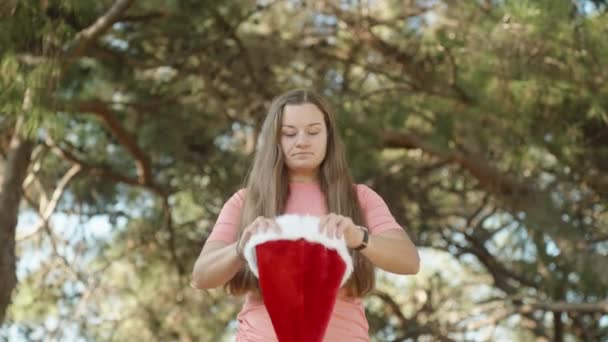 Egy Fiatal Felveszi Télapó Piros Kalapját Erdőben Karácsony Meleg Éghajlaton — Stock videók