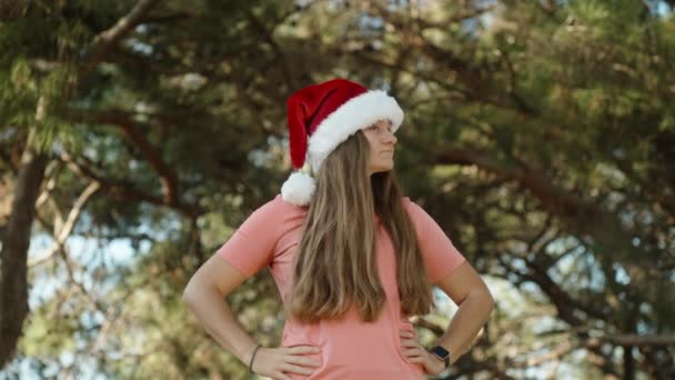 Een Jonge Vrouw Met Een Rode Kerstmuts Kijkt Rond Het — Stockvideo