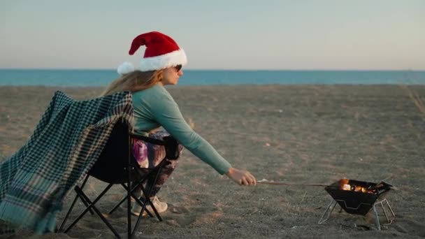 Різдво Біля Моря Молода Жінка Червоному Капелюсі Санта Смажить Зефір — стокове відео