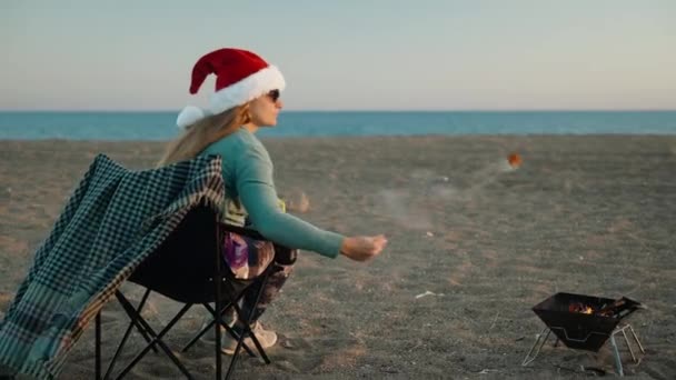 Молода Жінка Капелюсі Санта Їсть Смажені Зефіри Океані Новий Рік — стокове відео