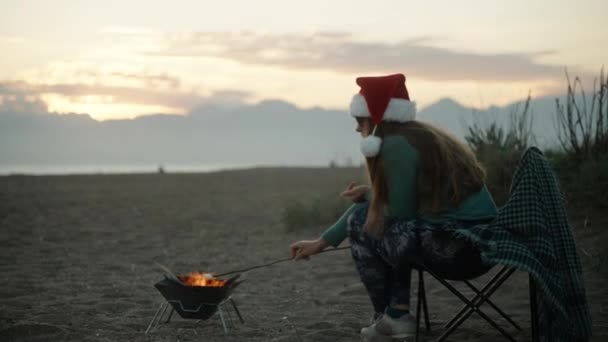 Молода Жінка Червоному Капелюсі Санта Смажить Зефір Пляжі Біля Моря — стокове відео