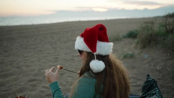 Μια Νεαρή Γυναίκα Στην Παραλία Κόκκινο Καπέλο Του Βασίλη Τρώει — Αρχείο Βίντεο