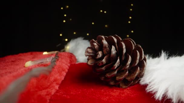 Een Dennenappel Ligt Hoed Van Kerstman Tegen Achtergrond Van Een — Stockvideo