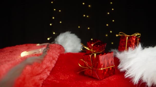 Три Маленькі Червоні Подарункові Коробки Лежать Капелюсі Санти Тлі Блимаючої — стокове відео