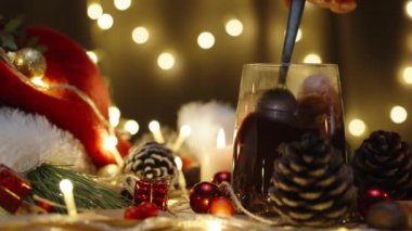 Kakaonun içinde marşmelov karıştırıyorum, arka planda ışıklardan oluşan bir çelenk. Mumlar ve dekorasyonlarla dolu bir Noel masası. Yavaş çekim.