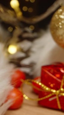 Dikey video. Kamera bir mumla Noel Baba 'nın şapkasının içinden geçiyor, masanın üzerinde duruyor. Noel süsleri sahnenin etrafını sardı. Dolly sürgülü aşırı yakın çekim içeride. Sonda
