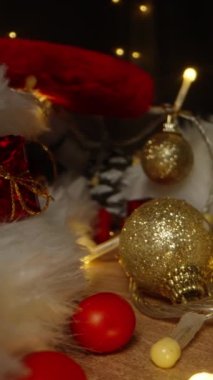 Dikey video. Noel gecesi mumları yakarım ve Noel ağacı için fenerlerle süslemeler masaya saçılmış olur. Yakın plan..