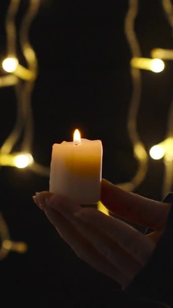 Pionowe Wideo Młoda Kobieta Trzyma Świecę Tle Płonącej Girlandy Zdmuchuje — Wideo stockowe