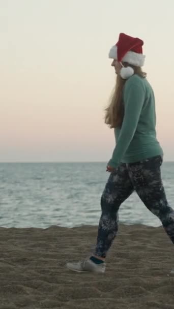 Вертикальне Відео Молода Жінка Святковому Червоному Капелюсі Йде Вздовж Пляжу — стокове відео