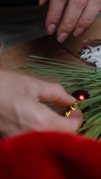 垂直录像 在车间的桌子上摆满了圣诞节的烂摊子 一个女孩把圣诞装饰品粘在家居装饰的装置上 — 图库视频影像