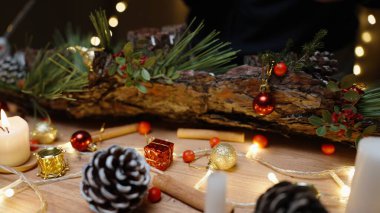 Noel günü atölyede bir kız çam ağacının kabuğuna böğürtlen ve oyuncak yapıştırıyor. Güzel bir ev dekorasyonu oluşturuluyor.