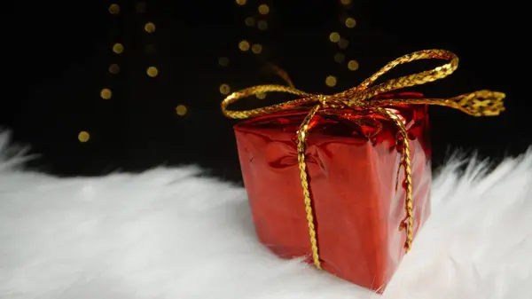 Небольшая Красная Подарочная Коробка Бантом Стоит Белой Меховой Шапке Фоне — стоковое фото