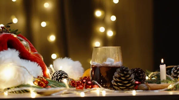 マシュマロを熱いココアに投げる デコレーションとスイーツのクリスマステーブル ろうそくとガーランドが燃えている — ストック写真