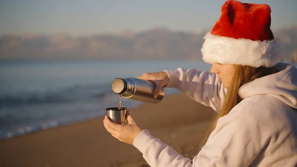 Una Giovane Donna Con Cappello Babbo Natale Versa Caldo Thermos — Foto Stock