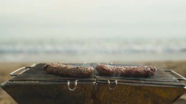 Deniz kenarında piknik, ızgaradaki etten çıkan duman, dumanın arasından denize kayan odak noktası..